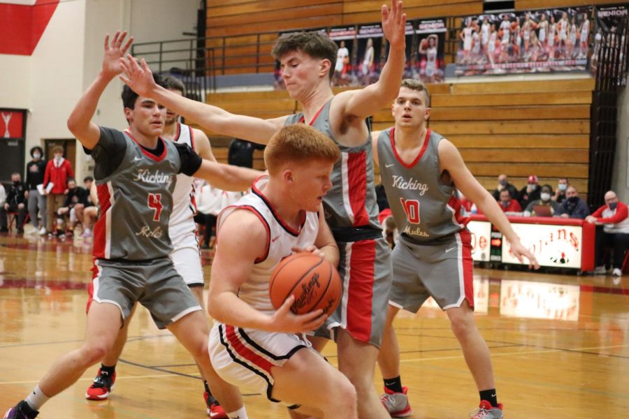 Junior Logan Frank protects the ball as he is flanked by Bedford players. Frank plays on the team as a guard.